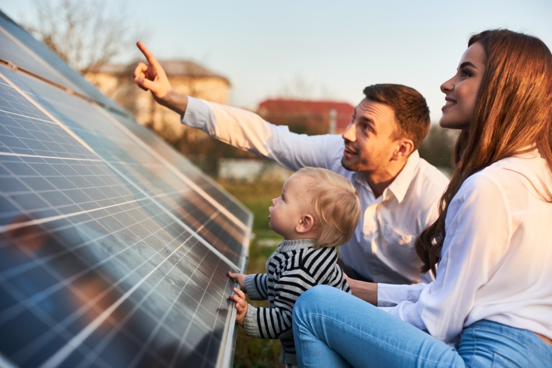 man and women sitting infront of a solar panel